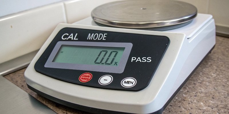 Calibrating a scale with a standard weight. A standard calibration weight placed on a digital scale