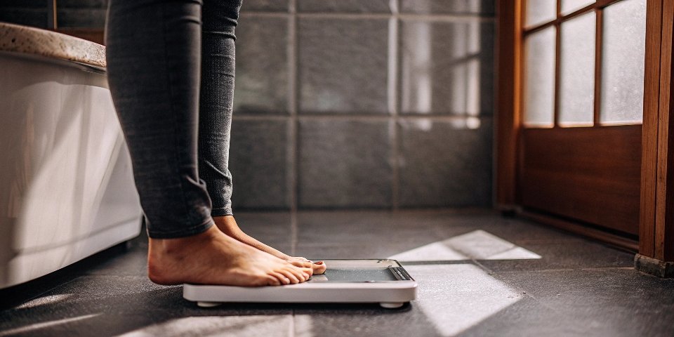 A person standing on a modern bathroom scale at home