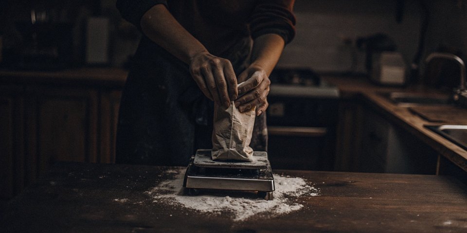 Checking Scale Accuracy at Home A person placing a 2kg bag of flour on a kitchen scale to verify its accuracy.