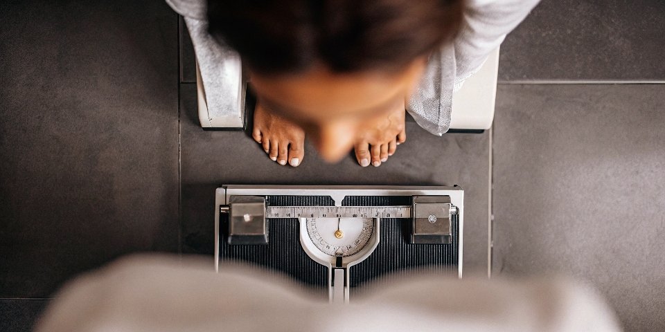Understanding Weight on Digital Scales A person looking down at a digital scale with a thoughtful expression