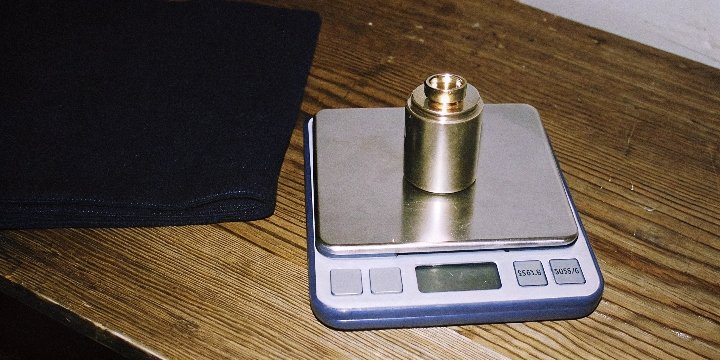 A 100g pocket scale with a small 100g calibration weight on its platform