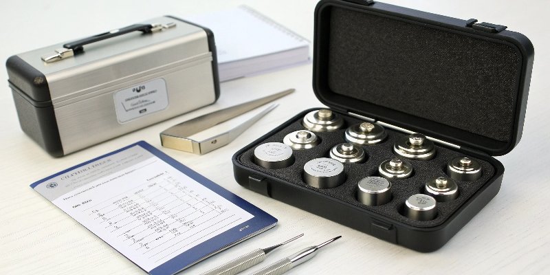 Essential Calibration Equipment A set of certified calibration weights in a case next to anti-static tweezers
