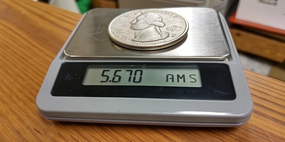 A US quarter coin being weighed on a scale A US quarter coin on a digital scale displaying 5.670 g