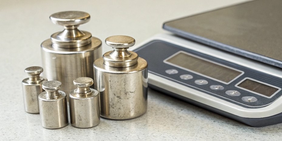 Linearity Test for Digital Scale Several different-sized calibration weights lined up next to a digital bench scale.