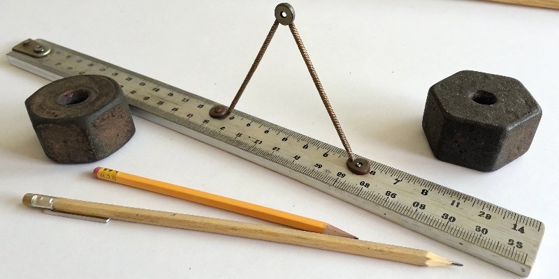 A DIY balance made from a ruler, a pencil, and items of known and unknown weight.