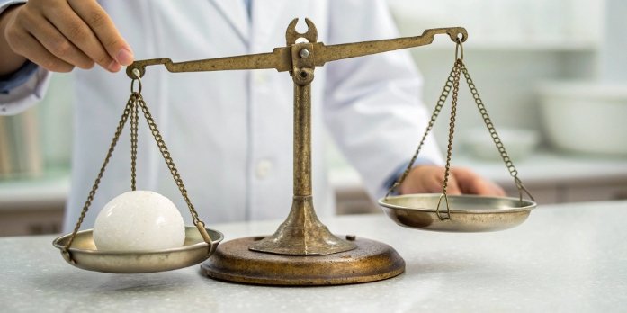 A laboratory balance comparing two objects to illustrate the measurement of mass vs weight