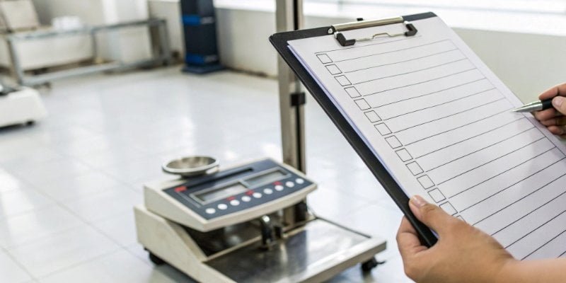 A checklist on a clipboard next to a commercial scale