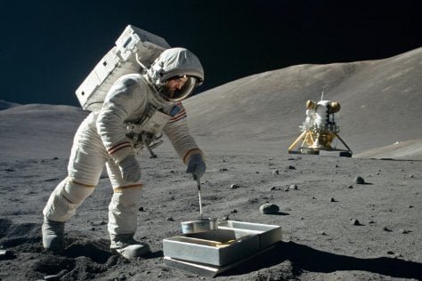 An astronaut weighing an object on the moon