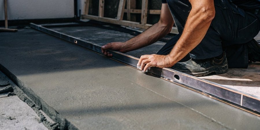 Checking floor for flatness A construction worker using a long level to check a concrete floor's evenness
