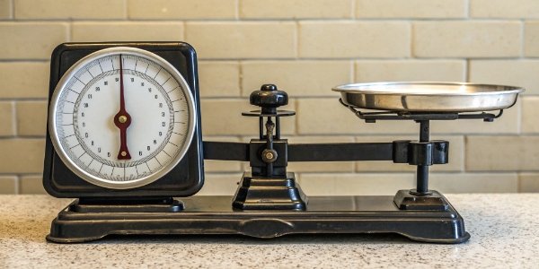 Mechanical vs. Electronic Scale Technology An old-fashioned mechanical dial scale side-by-side with a modern electronic scale with a bright digital display