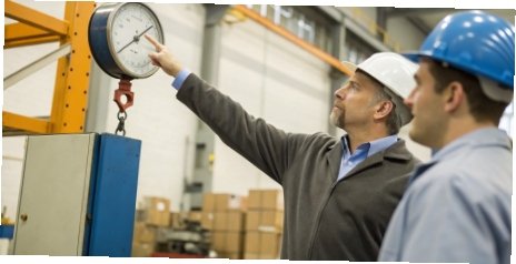 An engineer pointing to the capacity and accuracy specifications on an industrial scale's data plate.