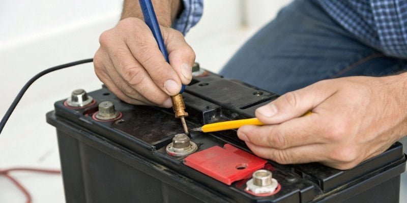 Cleaning battery contacts in a scale A person cleaning battery contacts with a pencil eraser.