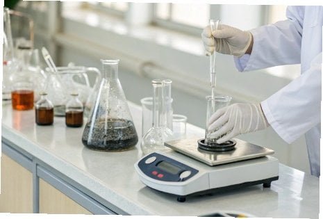 A laboratory balance being used for precise chemical measurement
