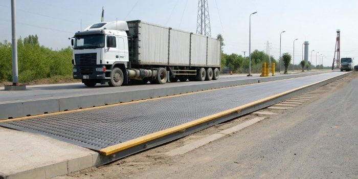 A large truck scale installed on a road, a truck is driving on it.