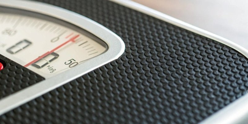 A close-up of a digital scale's display flickering next to a low battery symbol.