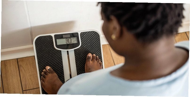 Why Scales Differ A person looking down at a digital scale with a questioning expression