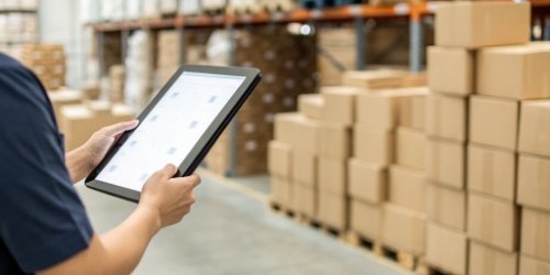 An image showing a comparison between a digital inventory record on a tablet and a physical pile of boxes, where the numbers do not match.