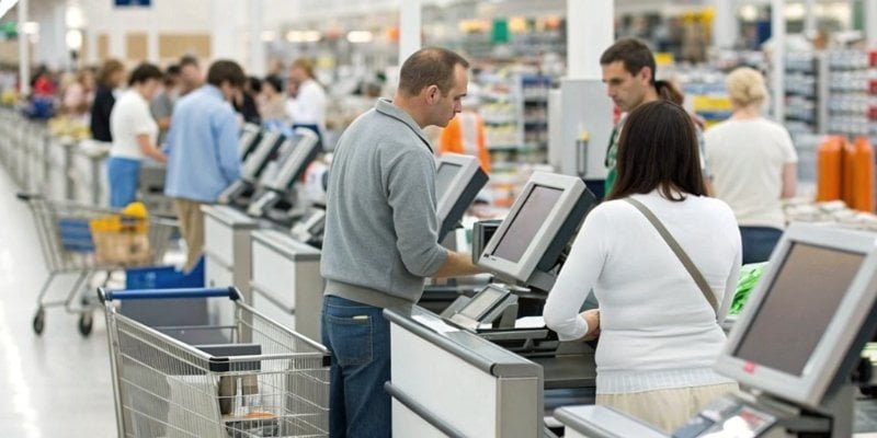 A busy supermarket checkout lane with multiple integrated devices