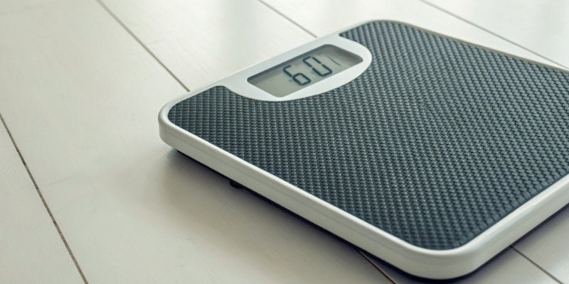 A digital scale on a plain background showing 60 kg