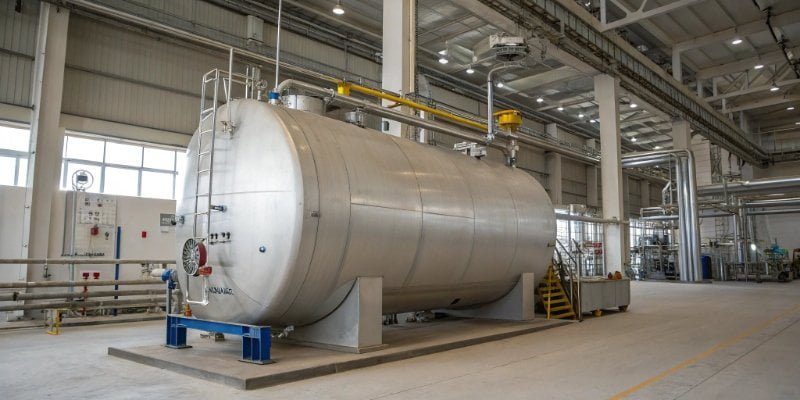 A large industrial mixing tank fitted with load cells for a tank weighing system in a chemical plant.