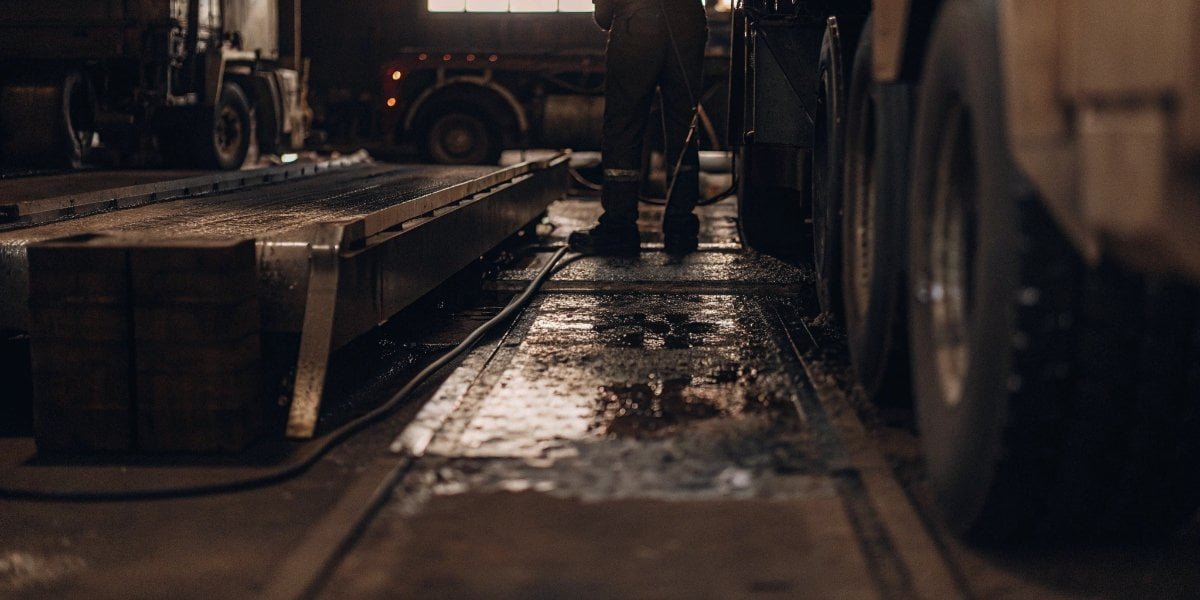 Maintenance worker cleaning under a truck scale weighbridge