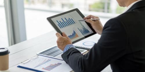 Software for Business Efficiency A business professional analyzing data on a tablet, with charts and graphs showing business growth.