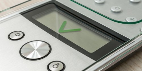 Close-up of a scale's screen showing a green checkmark for a successful weigh-in