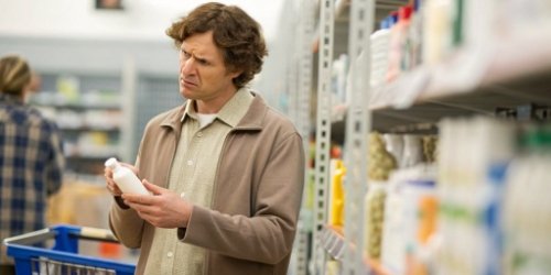 A customer looking confused at a product label in a store