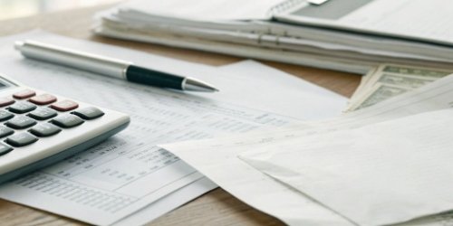 A calculator and receipts on a desk showing business expenses