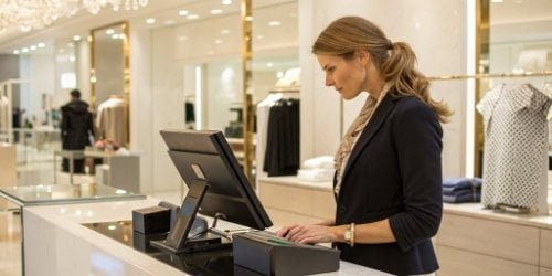 A sleek, co-branded smart PC scale being used by a cashier in a high-end retail store.