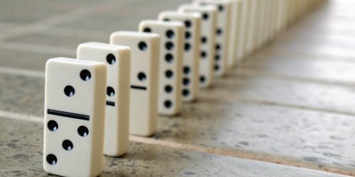 A line of falling dominoes, symbolizing how one small problem can cause a chain reaction of failures