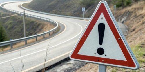 A road sign with a warning symbol indicating potential challenges ahead.