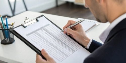 A person filling out a scorecard or checklist on a clipboard.