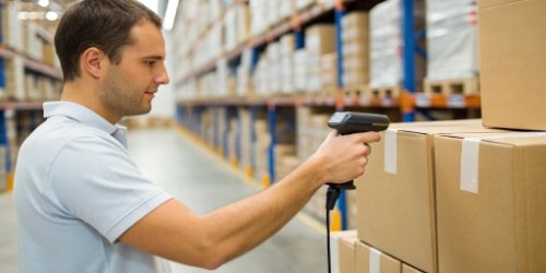 A warehouse worker scanning a serialized label on a box with a handheld scanner
