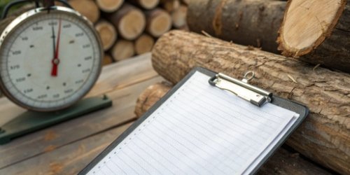 A clipboard with handwritten logs next to a scale, with some numbers visibly smudged or hard to read.