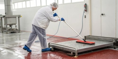 A worker easily cleaning a hygienically designed slaughterhouse scale.