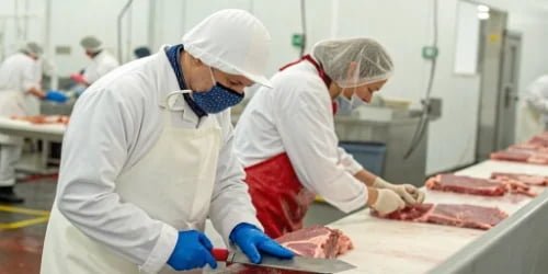 a supervisor training a meat cutter on a specific technique