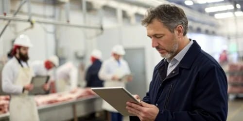 A manager reviewing a focused KPI report on a tablet in a slaughterhouse