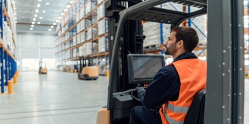 A forklift operator looks at a screen on the vehicle that displays the destination for the pallet being carried.