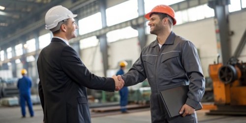 Successful Business Partnership Two business professionals shaking hands in an industrial setting